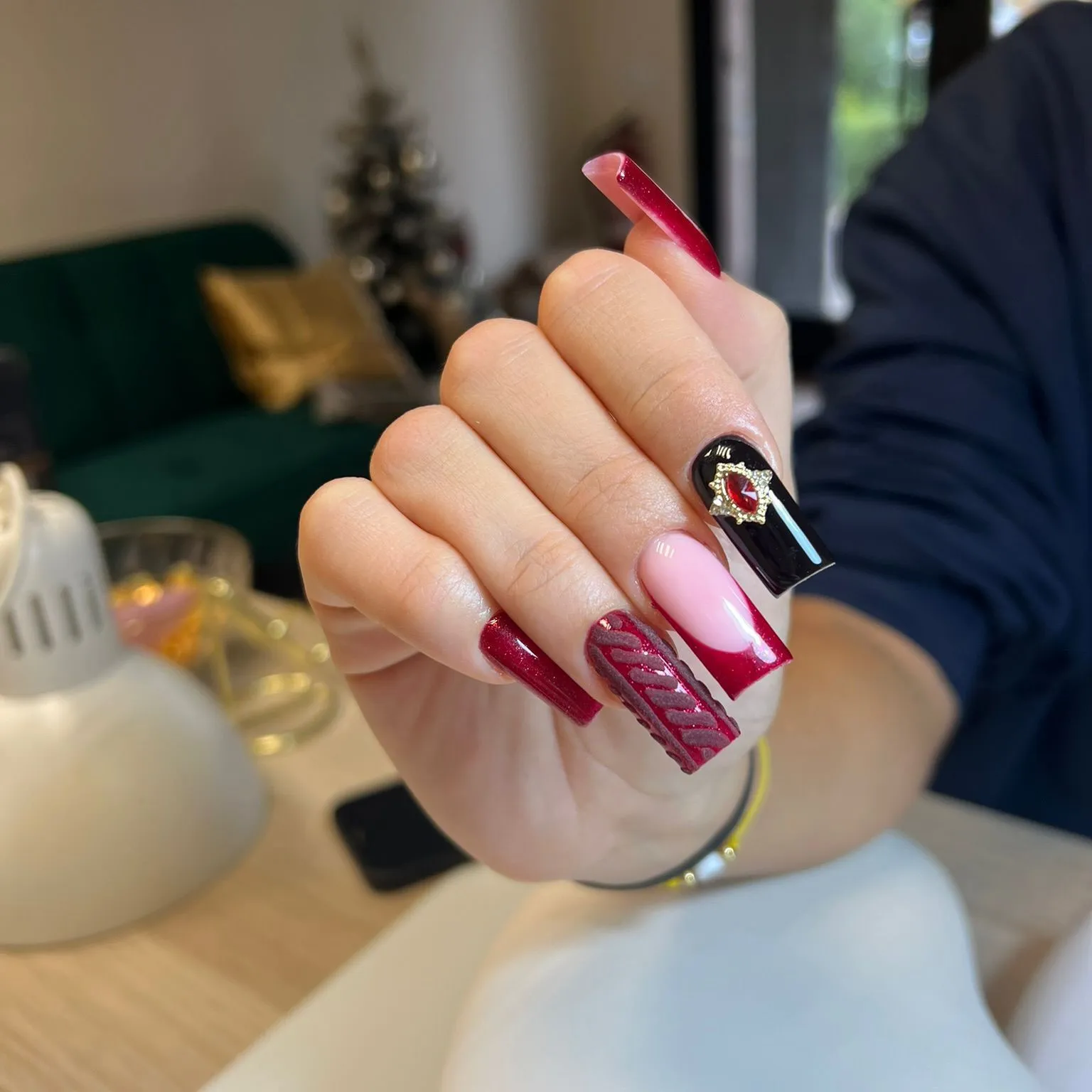 Uñas coffin en rojo y negro con textura de jersey y gema