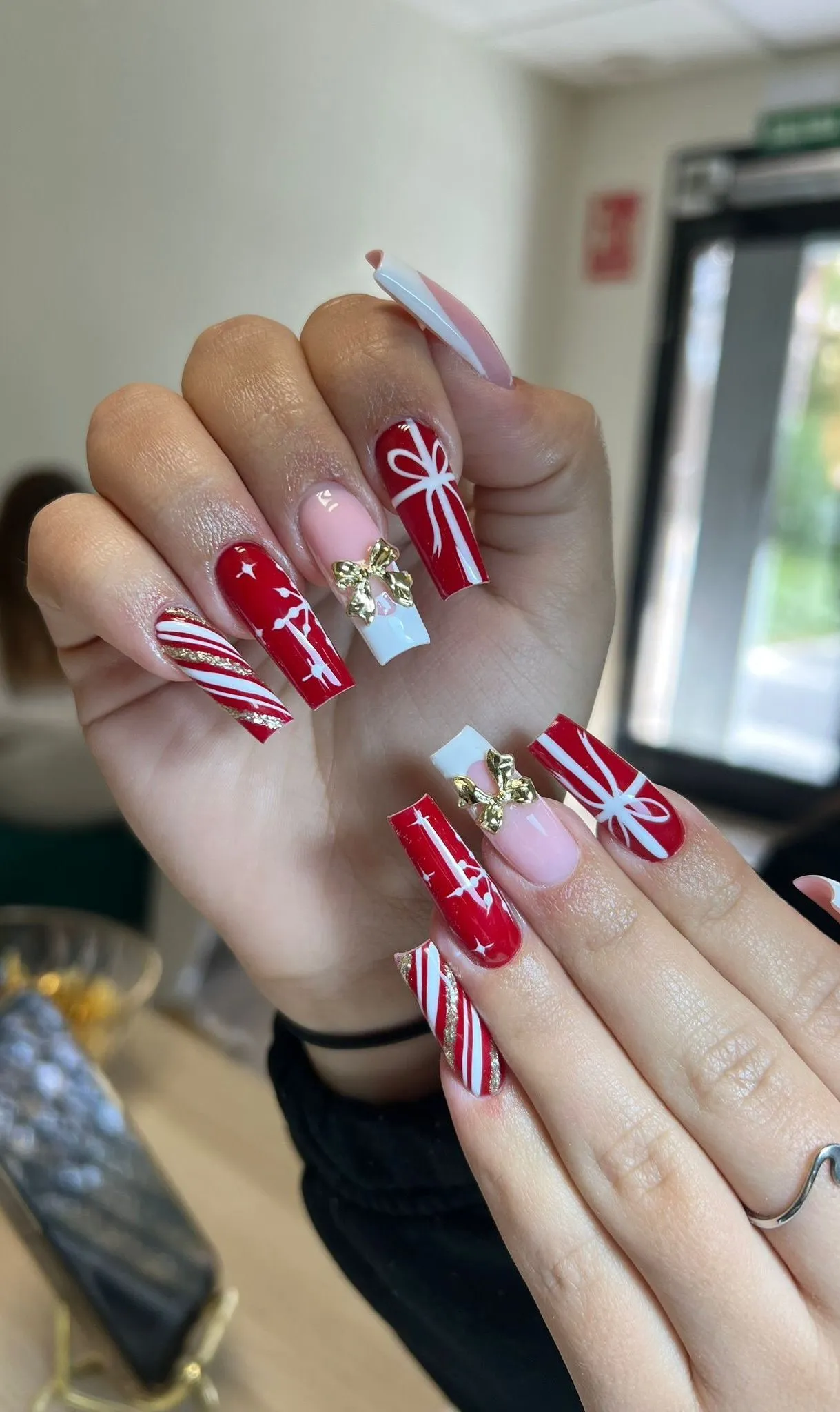 Nail art navideño en rojo con lazos y bastones de caramelo