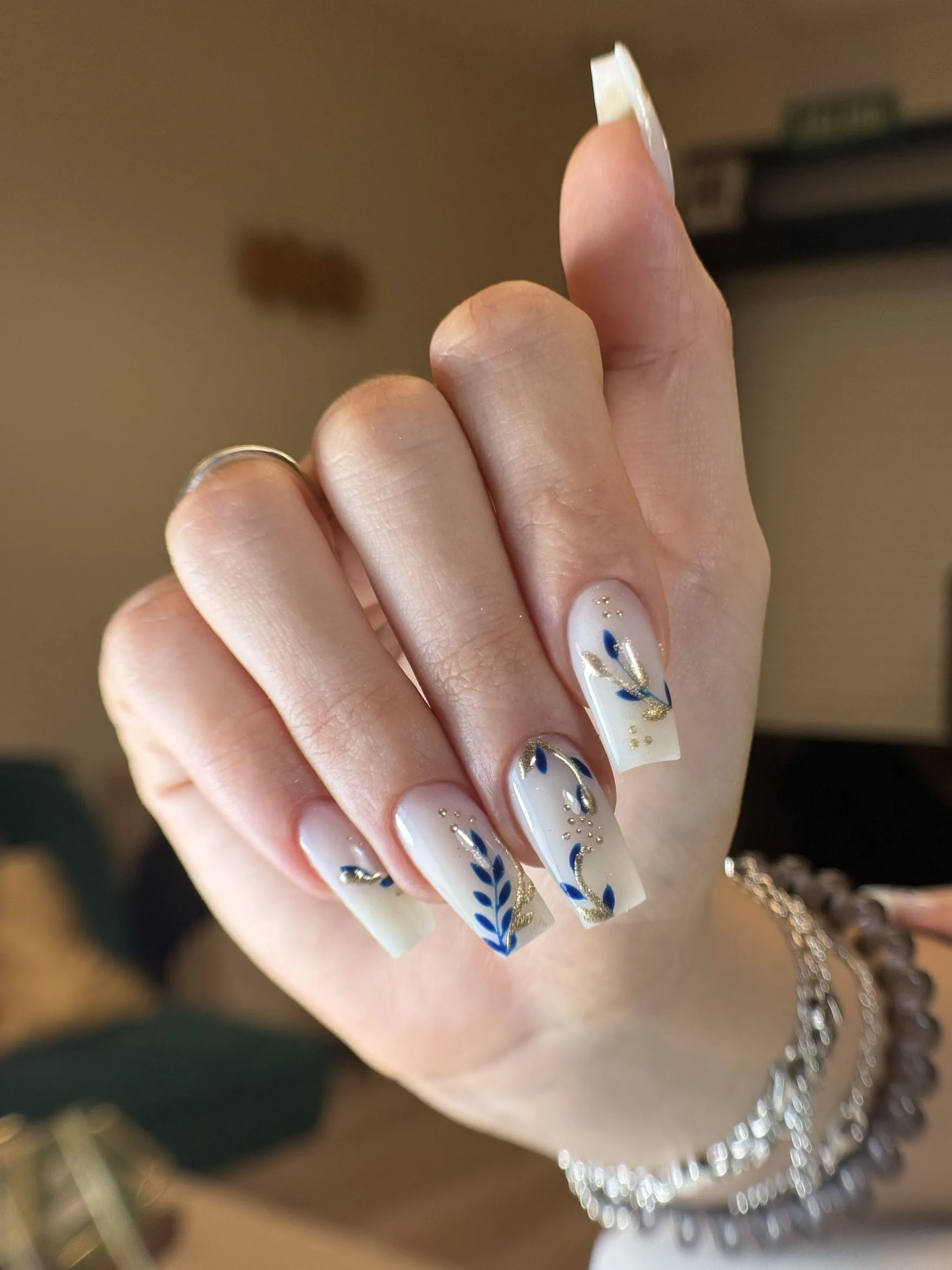 Uñas coffin nude con hojas en azul marino y dorado